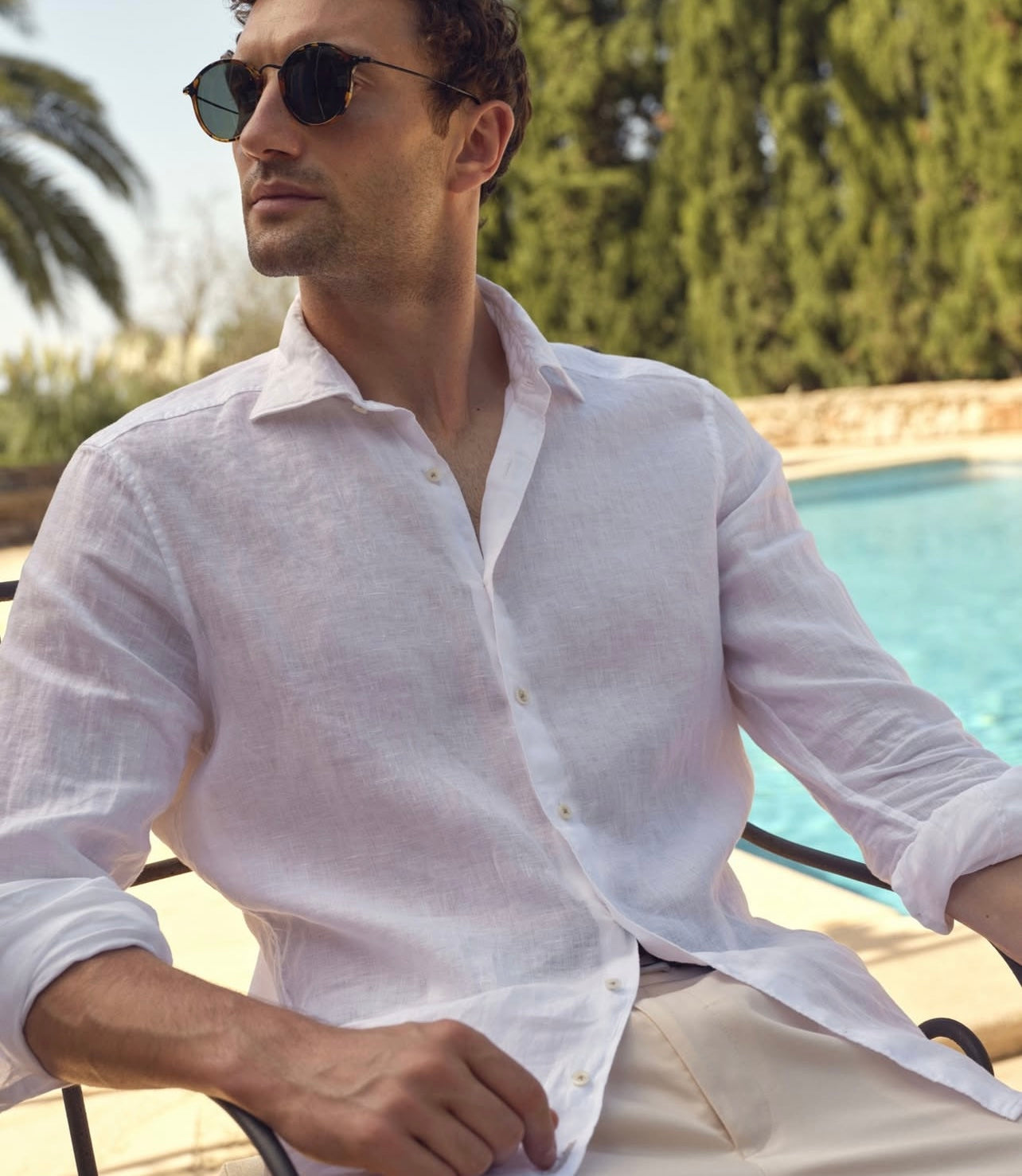 Man wearing a white linen shirt by a poolside