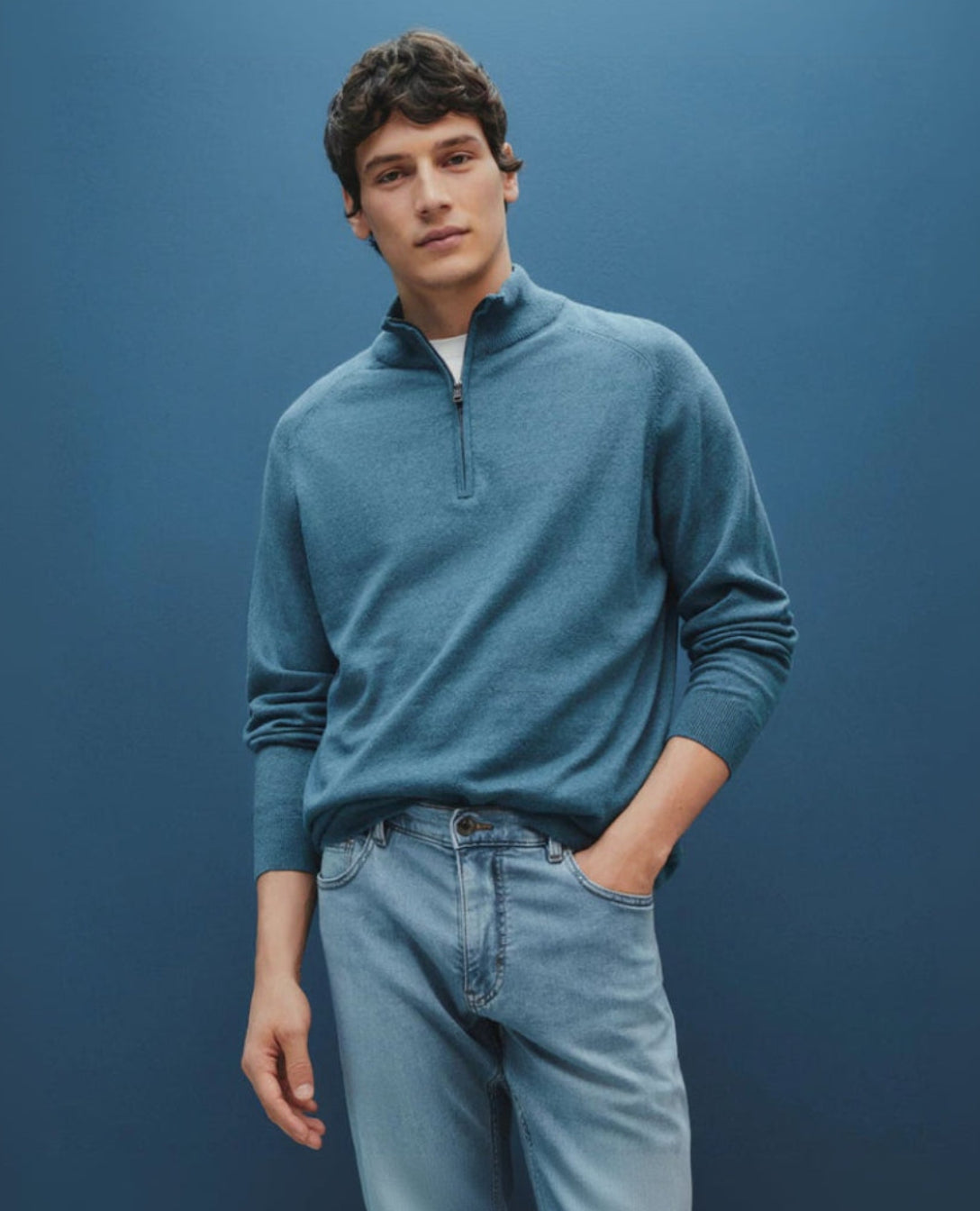 Man wearing a blue sweater and jeans against a blue background