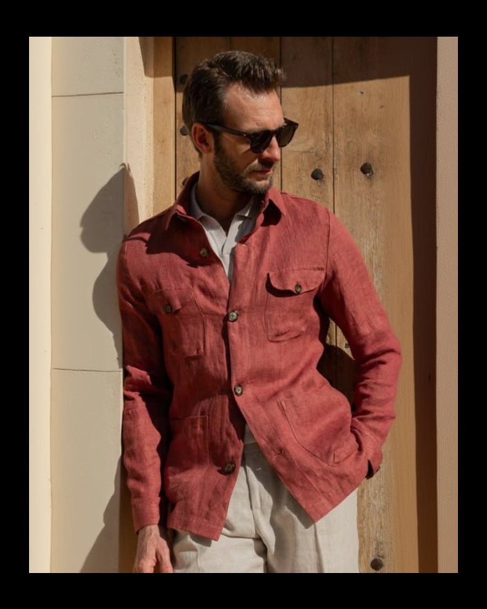 Man wearing a red jacket and sunglasses against a wooden door.